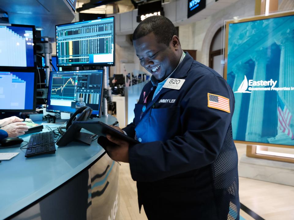 A smiling trader works on the floor of the New York Stock Exchange.