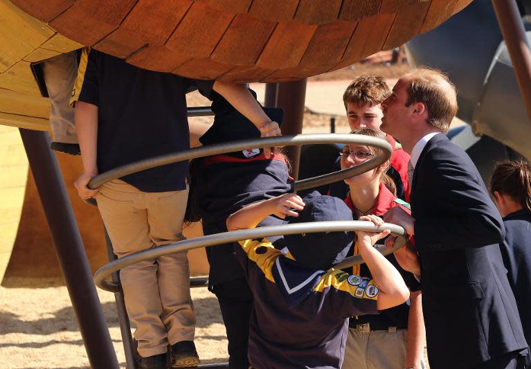 Prince William (R) watches as children play on an apparatus while he walks through the Pod Playground at the National Arboretum in Canberra on April 24, 2014