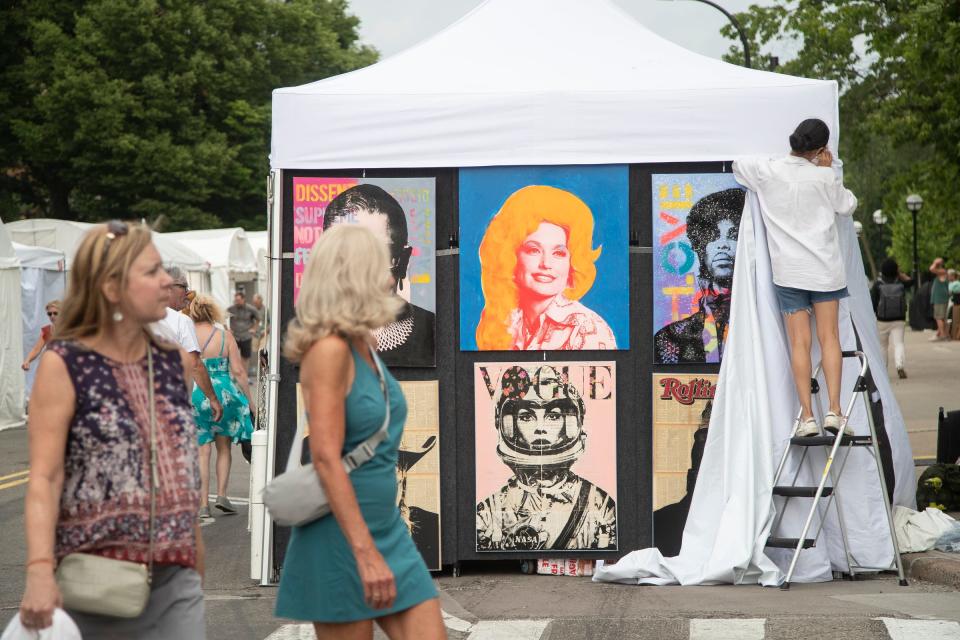 Evelyn Chavez rolls down the tent cover at artist Dane Shue's tent on State Street before the coming storm which temporarily closes the annual Ann Arbor Art Fair from 3-5 p.m. in Ann Arbor on Thursday, July 20, 2023.