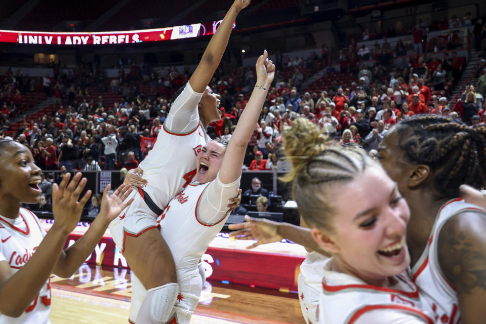 UNLV forward Alyssa Brown (44) and center Erica Collins (31) celebrate with teammates after a win over San Diego State in an NCAA college basketball game for the championship of the Mountain West women's tournament Wednesday, March 13, 2024, in Las Vegas. (AP Photo/Ian Maule)