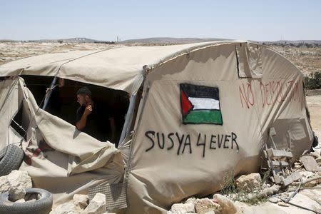 A Palestinian man looks out of a tent in Susiya village, south of the West Bank city of Hebron July 20, 2015. REUTERS/Mussa Qawasma