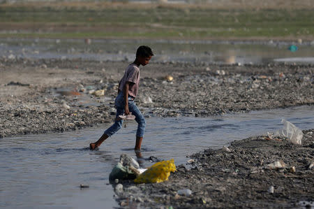 A boy crosses a drain on the banks of the river Ganges in Kanpur, India, April 4, 2017. REUTERS/Danish Siddiqui