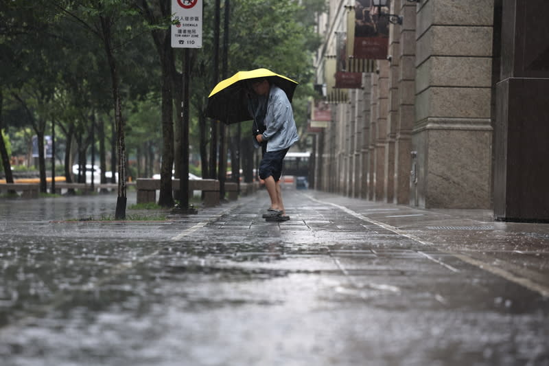 氣象署23日表示，未來一周天氣仍悶熱，24日白天雙北等11縣市亮起高溫燈號，氣溫上看攝氏36度以上；各地天氣多雲到晴，須注意午後雷陣雨。圖為台北市信義區民眾撐傘遮擋風雨。（中央社）