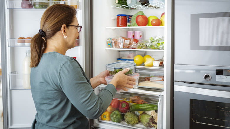 woman place containers in refrigerator