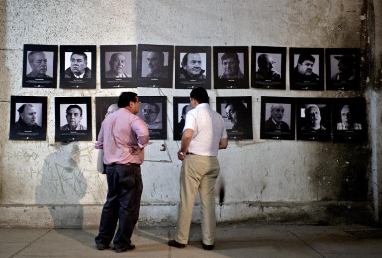 Members of the "Former Political Prisoners of the National Stadium" human rights association stand next to pictures in a gallery that once served as a jail for prisoners in the National Stadium in Santiago, Chile on February 10, 2015