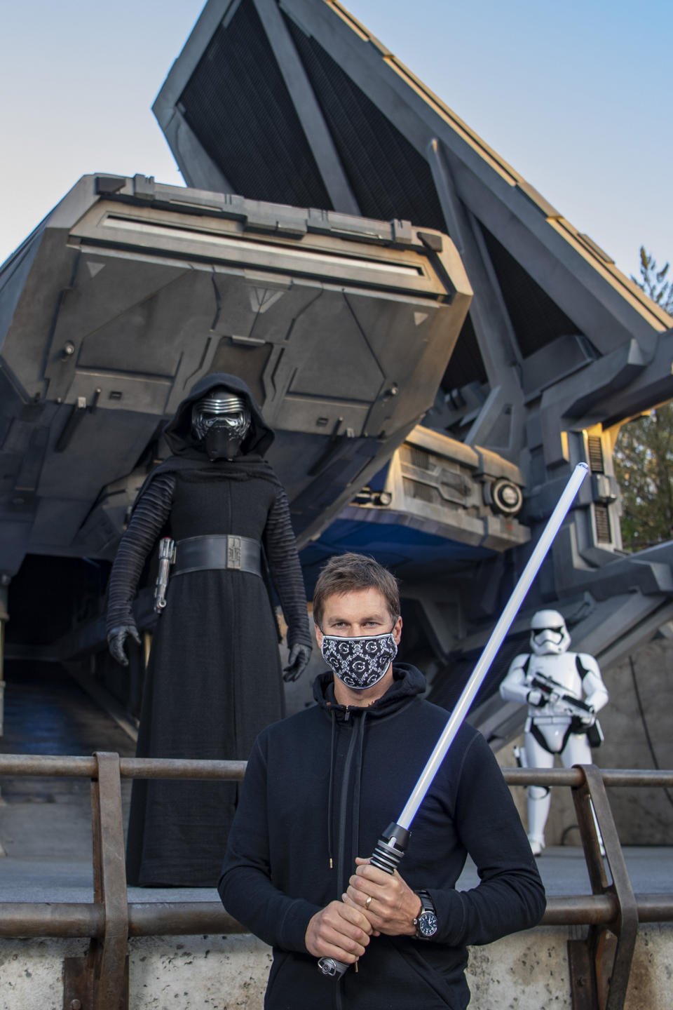 In this photo provided by Walt Disney World, NFL star Tom Brady visits Star Wars: Galaxy's Edge inside Disney's Hollywood Studios at Walt Disney World Resort in Lake Buena Vista, Fla., Monday, April 5, 2021. A mask-wearing Brady visited the Star Wars-themed section of Walt Disney World with his family and friends, two months after he led the Bucs to a Super Bowl win against the Chiefs. (Matt Stroshane/Disney World via AP)