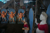 An Indian artisan speaks on a phone as he works on idols of Hindu gods and goddesses ahead of Durga Puja festival in Gauhati, India, Friday, Oct. 16, 2020. Health officials have warned about the potential for the coronavirus to spread during the upcoming religious festival season, which is marked by huge gatherings in temples and shopping districts. (AP Photo/Anupam Nath)