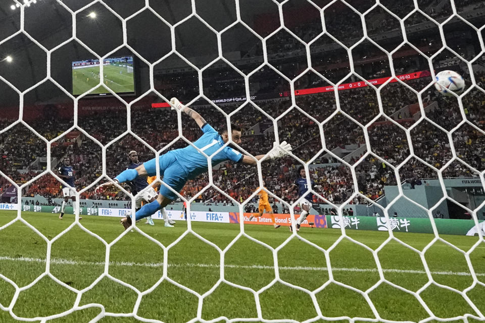 Cody Gakpo of the Netherlands, partially hidden, scores his side's opening goal during the World Cup group A soccer match between Netherlands and Ecuador, at the Khalifa International Stadium in Doha, Qatar, Friday, Nov. 25, 2022. (AP Photo/Natacha Pisarenko)