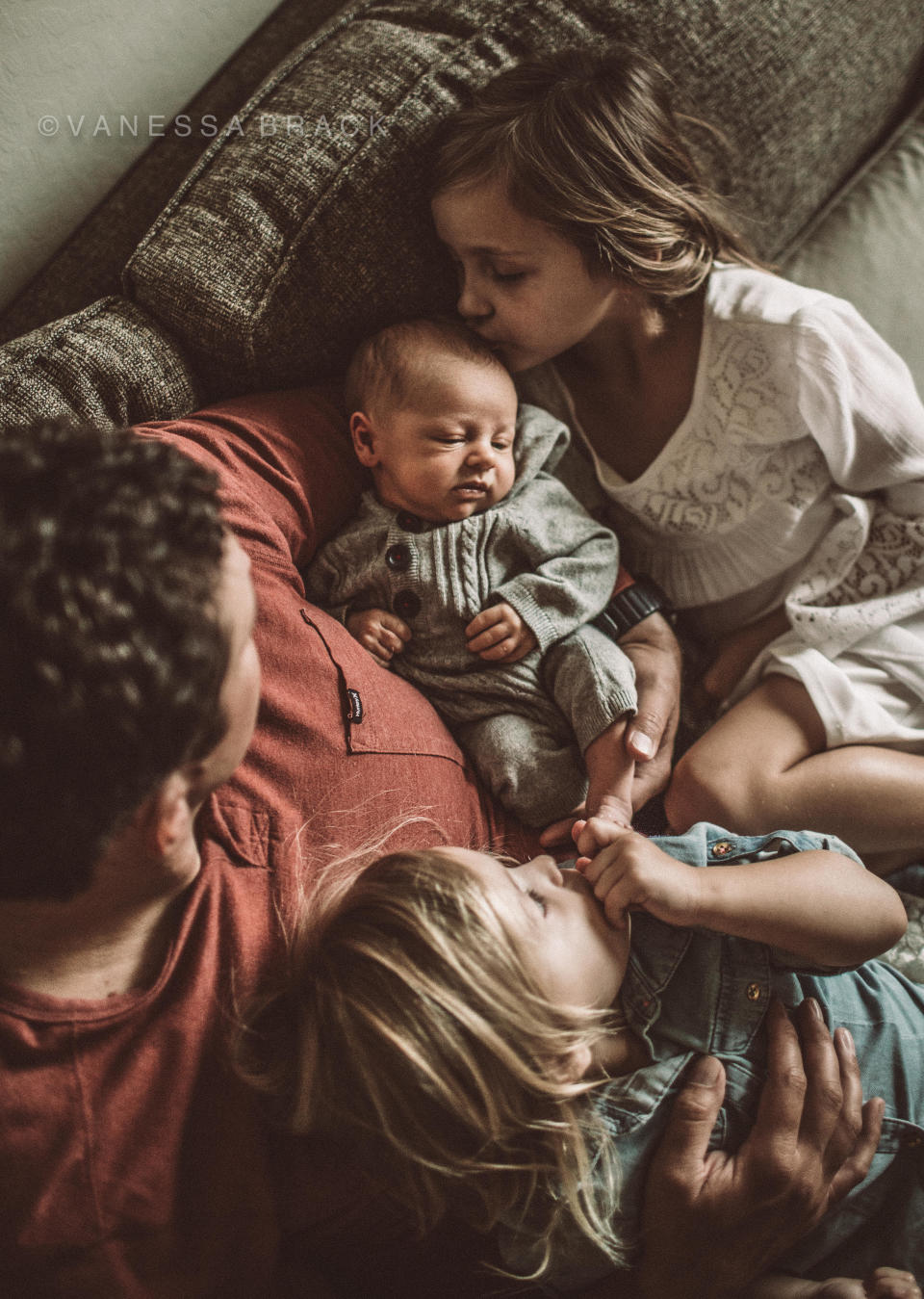 "This dad snuggles with his girls as they welcome and get to know their new baby brother."