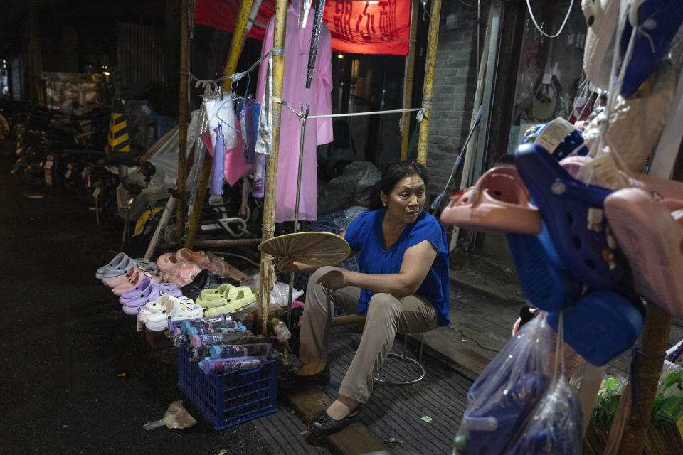 A vendor selling slippers and umbrellas during a rainy day waits for customers in Beijing, Thursday, July 27, 2023. Chinese leader Xi Jinping's government is promising to drag the economy out of a crisis of confidence aggravated by tensions with Washington, wilting exports, job losses and anxiety among foreign companies about an expanded anti-spying law. (AP Photo/Ng Han Guan)