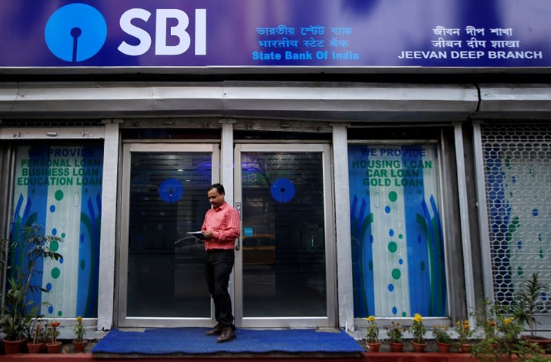 FILE PHOTO: A man checks his mobile phones in front of State Bank of India (SBI) branch in Kolkata