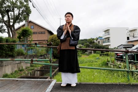 A buddhist monk prays near the Kyoto Animation building which was torched by arson attack, in Kyoto