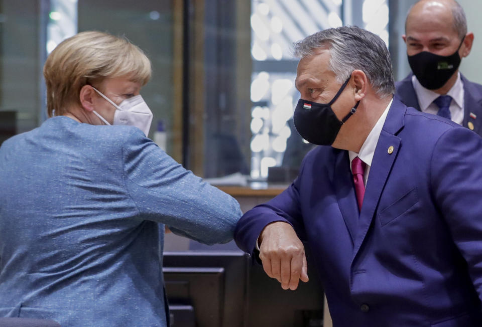 German Chancellor Angela Merkel, left, greets Hungary's Prime Minister Viktor Orban, center, with an elbow bump during a round table meeting at an EU summit at the European Council building in Brussels, Thursday, Oct. 1, 2020. European Union leaders are meeting to address a series of foreign affairs issues ranging from Belarus to Turkey and tensions in the eastern Mediterranean. (Olivier Hoslet, Pool via AP)