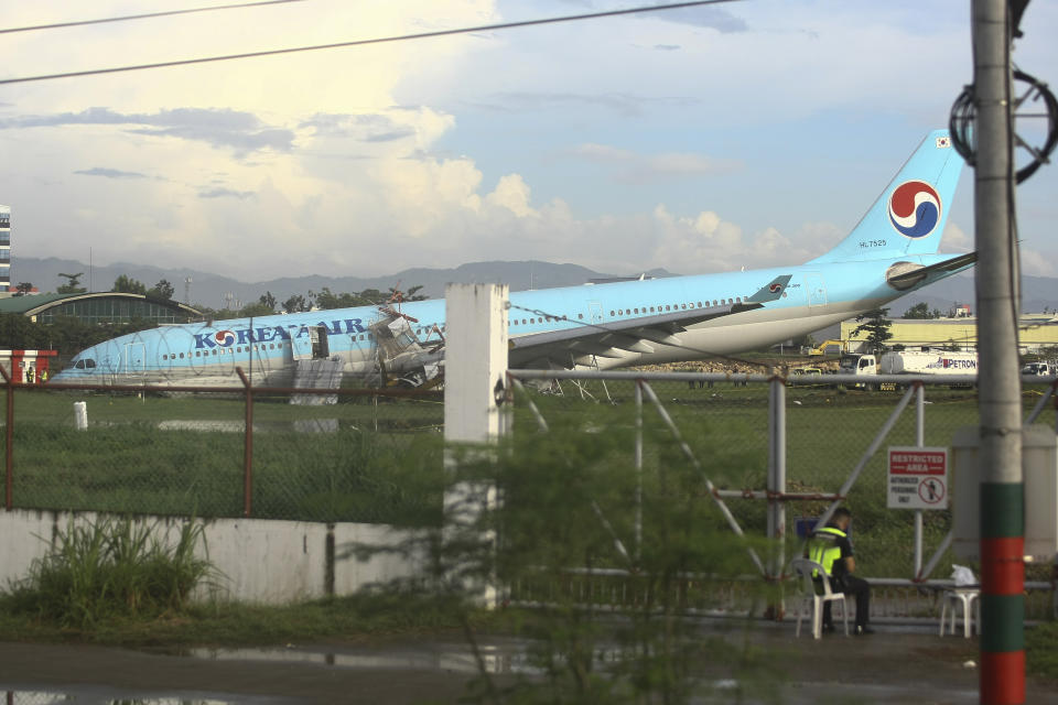 A security man keeps watch beside a damaged Korean Air plane after it overshot the runway at the Mactan-Cebu International Airport in Cebu, central Philippines early Monday Oct. 24, 2022. The Korean Air plane overshot the runway while landing in bad weather in the central Philippines late Sunday, but authorities said all 173 people on board were safe. (AP Photo/Juan Carlo De Vela)