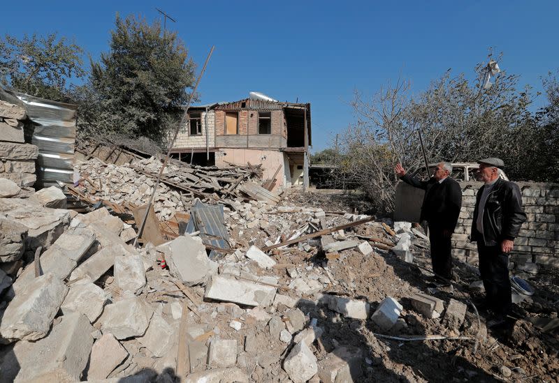 Men stand next to the ruins of a house that was destroyed by recent shelling during the military conflict over the breakaway region of Nagorno-Karabakh, in Martuni