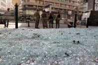 FILE - In this Oct. 14, 2021, file photo, glass from broken windows litters a street as Lebanese army soldiers stand guard after deadly clashes erupted along a former 1975-90 civil war front-line between Muslim Shiite and Christian areas, in Ain el-Rumaneh neighborhood, Beirut, Lebanon. The shootout on the streets of Beirut between rival Christian and Muslim groups has revived memories of the country's 1975-90 civil war and fired up sectarian passions in a country that never dealt with the causes of its violent past. (AP Photo/Bilal Hussein, File)