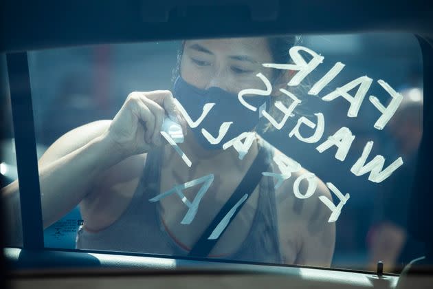 Donna Young, of IATSE Local 700 Motion Picture Editors Guild, writes a message in support of fair wages for all on a union member's car during a rally on Sept. 26 in Los Angeles. (Photo: Myung J. Chun via Getty Images)