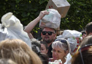 Local residents, many of whom fled the war, gather to hand out donated items such as medicines, clothes, and personal belongings to their relatives on the territories occupied by Russia, in Zaporizhzhia, Ukraine, Sunday, Aug. 14, 2022. Volunteers transport these items across the frontline and distribute them to addresses at their own risk. (AP Photo/Andriy Andriyenko)