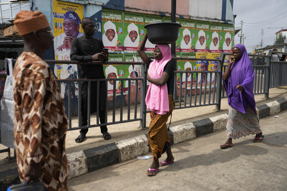 People walk past posters of Presidential candidate Bola Tinubu of the All Progressives Congress in Lagos, Nigeria Monday, Feb. 27, 2023. Each of the three frontrunners in Nigeria's hotly contested presidential election claimed they were on the path to victory Monday, as preliminary results trickled in two days after Africa's most populous nation went to the polls. (AP Photo/Sunday Alamba)