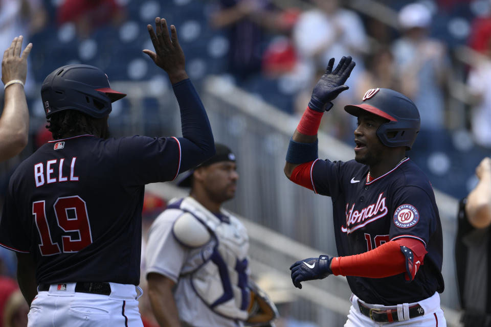 Washington Nationals' Victor Robles celebrates his three-run home run with Josh Bell (19) during the fourth inning of the first baseball game of a doubleheader against the Colorado Rockies, Saturday, May 28, 2022, in Washington. Rockies catcher Elias Diaz is at back center.(AP Photo/Nick Wass)