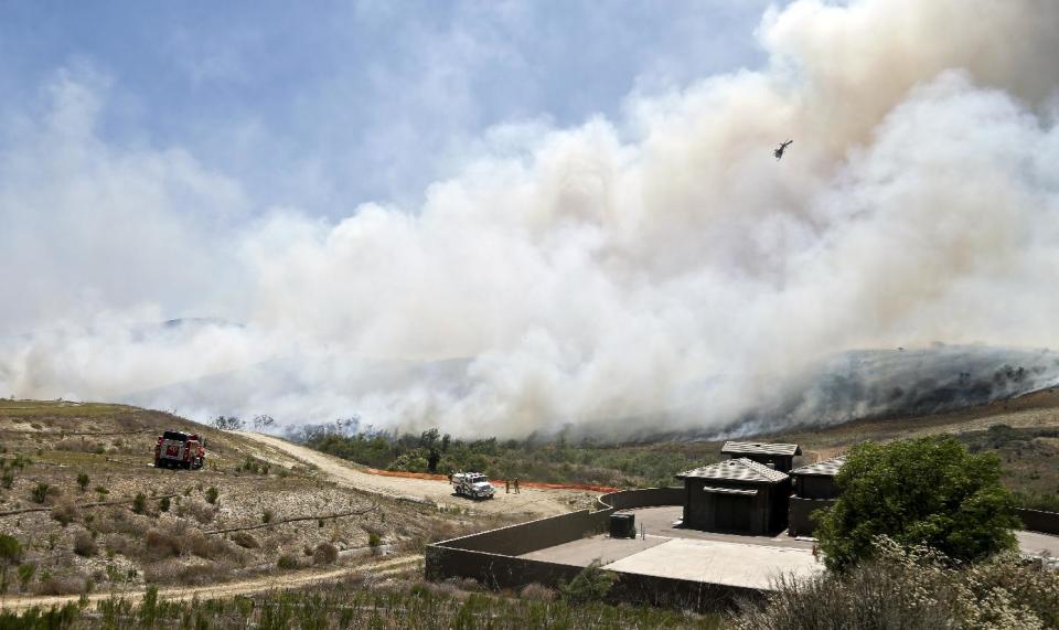 Smoke rises from a canyon where a wild fire is burning Tuesday, May 13, 2014, in San Diego. Wildfires destroyed a home and forced the evacuation of several others Tuesday in California as a high-pressure system brought unseasonable heat and gusty winds to a parched state that should be in the middle of its rainy season. (AP Photo)