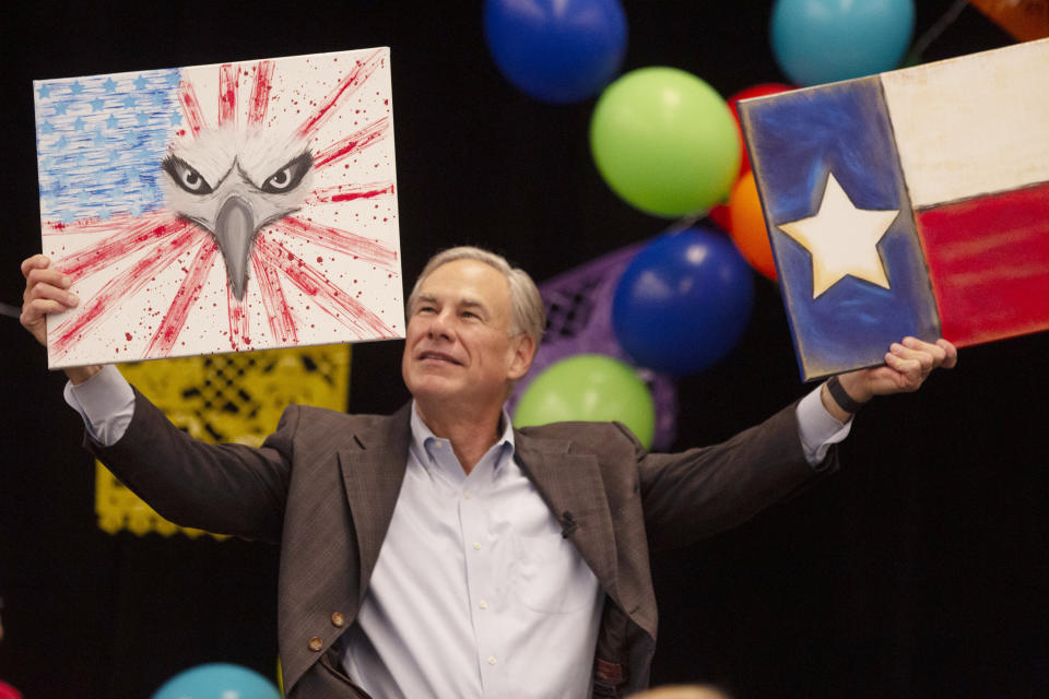 Gov. Greg Abbott holds up two paintings he received as a gift at the Midland Chapter of the Republican National Hispanic Assembly's Reagan Lunch at the Bush Convention Center, Friday, Nov. 5, 2021, in Midland, Texas. (Jacob Ford/Odessa American via AP)