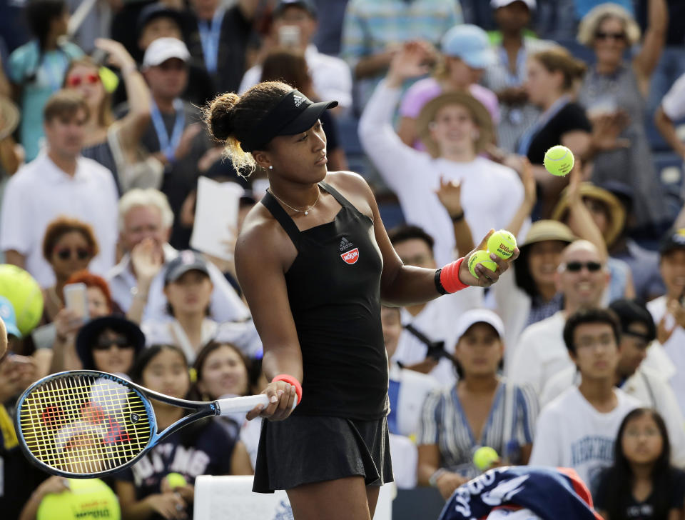 Naomi Osaka, of Japan, hits tennis balls to fans after defeating Aliaksandra Sasnovich, of Belarus, during the third round of the U.S. Open tennis tournament, Saturday, Sept. 1, 2018, in New York. (AP Photo/Kevin Hagen)