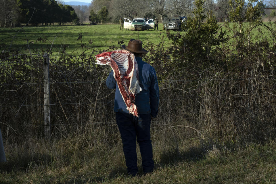 Carrying a rack of beef, Mapuche leader Juan Antonio Huichalaf Malpu quarrels with police who have arrived to evict his family from a property the family claims as ancestral lands in Carimallin, southern Chile, on Sunday, June 26, 2022. In the end the family vacated the area. (AP Photo/Rodrigo Abd)