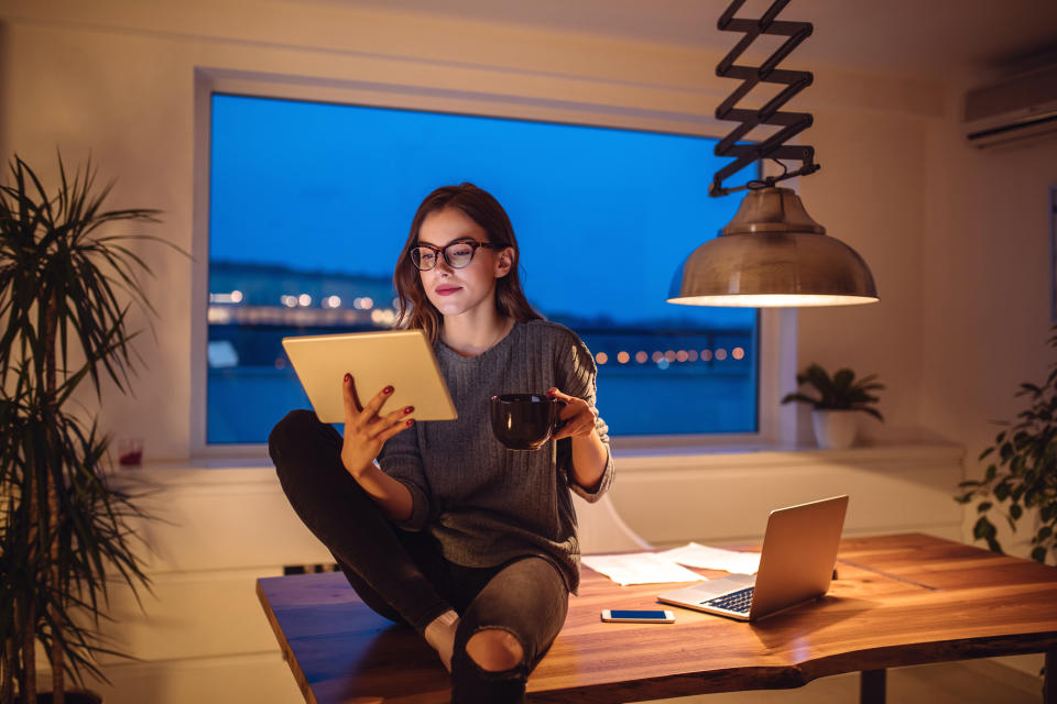 Beautiful woman drinking coffee and relaxing at home at twilight.