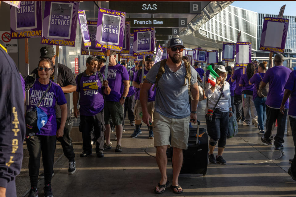 Passengers on the way to departing terminal negotiate through scores of Los Angeles city workers picketing on Tuesday, August 8, 2023, at LAX.