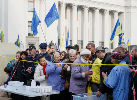 People receive hot tea in a makeshift kitchen in a tent camp set in protest near the Ukrainian parliament building in Kiev, Ukraine October 19, 2017. REUTERS/Gleb Garanich