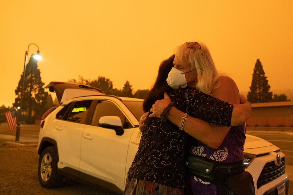 Evacuated residents hug near State Route 89 during the Dixie Fire in Greenville, Calif., on July 24. (David Odisho / Bloomberg via Getty Images)