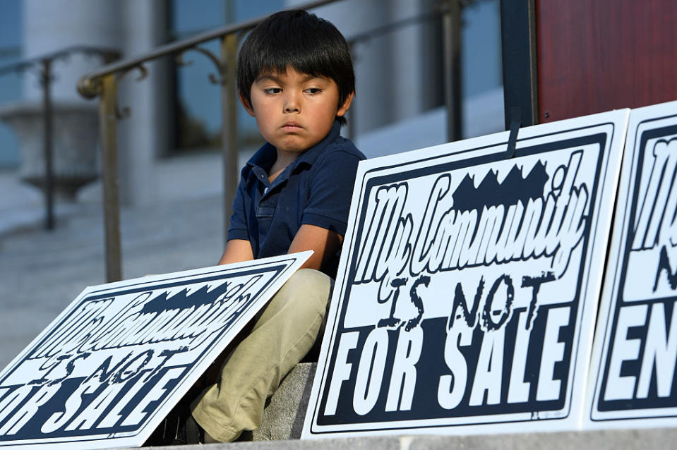 Giovanni Rodriguez, 5, sits next to signs that protests the lack of affordable housing in Denver.