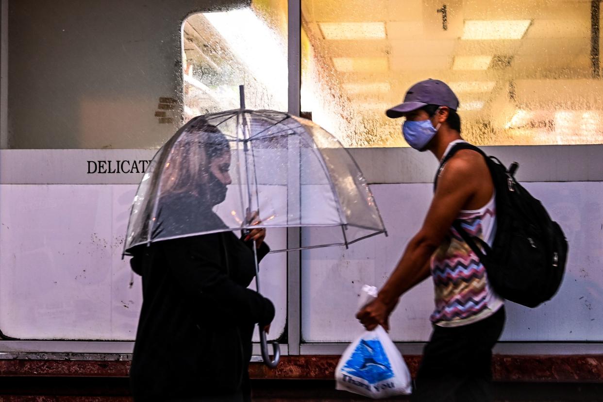 People walk in the street during a heavy rain and wind as tropical storm Eta approaches south of Florida, in Miami, Florida on November 8, 2020. (Chandan Khanna/AFP via Getty Images)