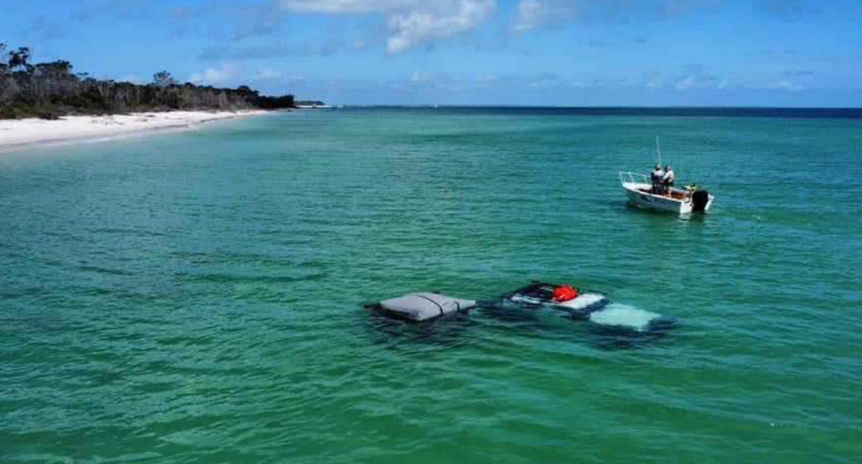 A 4WD and camper trailer completely submerged in water after getting bogged at a beach on K'gari.