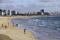 FILE — Beachgoers walk along South Beach, March 15, 2020, in Miami Beach, Fla. A small but well-publicized group of cryptocurrency enthusiasts called City Coins, is asking Miami and New York to accept the equivalent of millions of dollars in a new cryptocurrency scheme that has political leaders in other cities clamoring to get in on the deal. (AP Photo/Lynne Sladky, File)