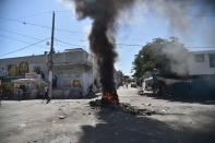 <p>Haitian people walk a street before a smouldering barricade in central Port-au-Prince, July 9, 2018, following two days of deadly looting and arson triggered by a quickly-aborted government attempt to raise fuel prices. (Photo: Hector Retamal/AFP/Getty Images) </p>