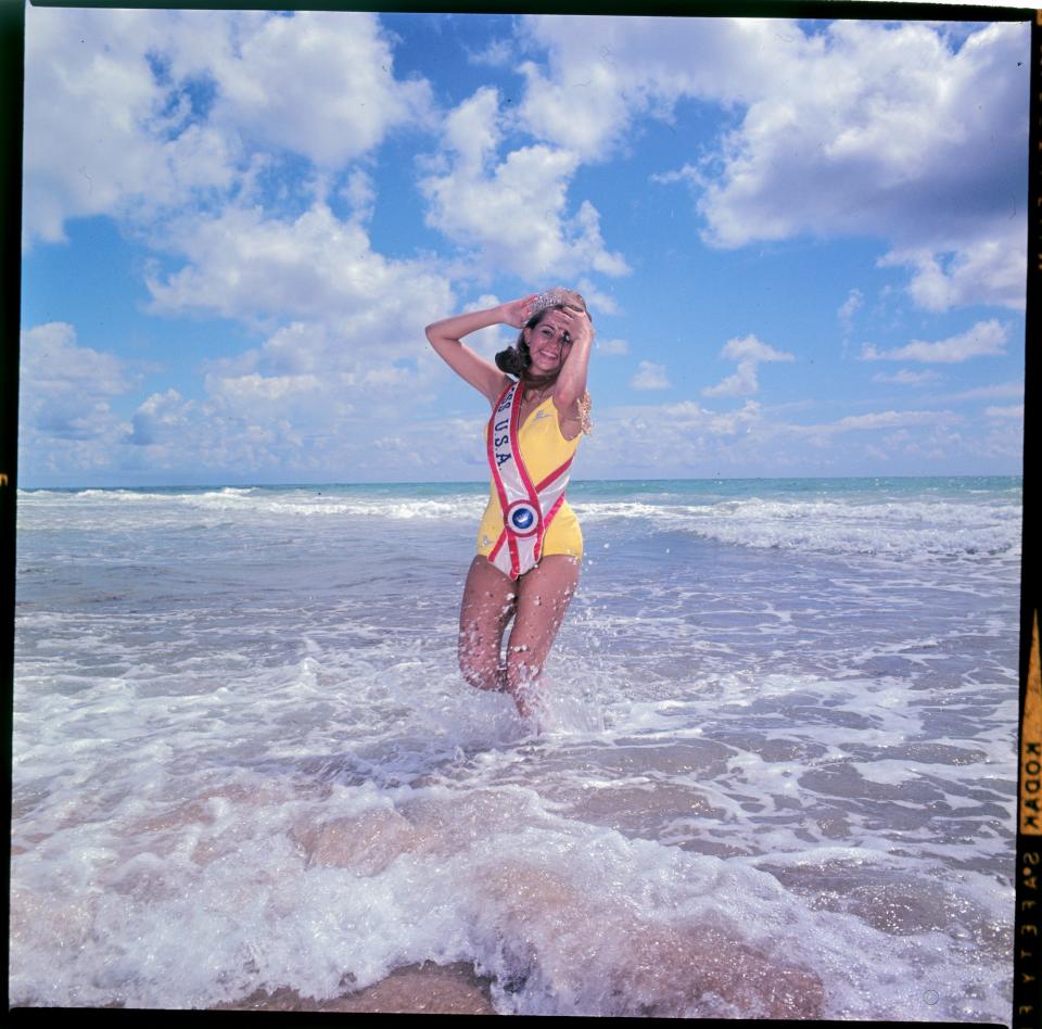 Miss USA 1967 Sylvia Louise Hitchcock poses in the ocean wearing her tiara and sash.