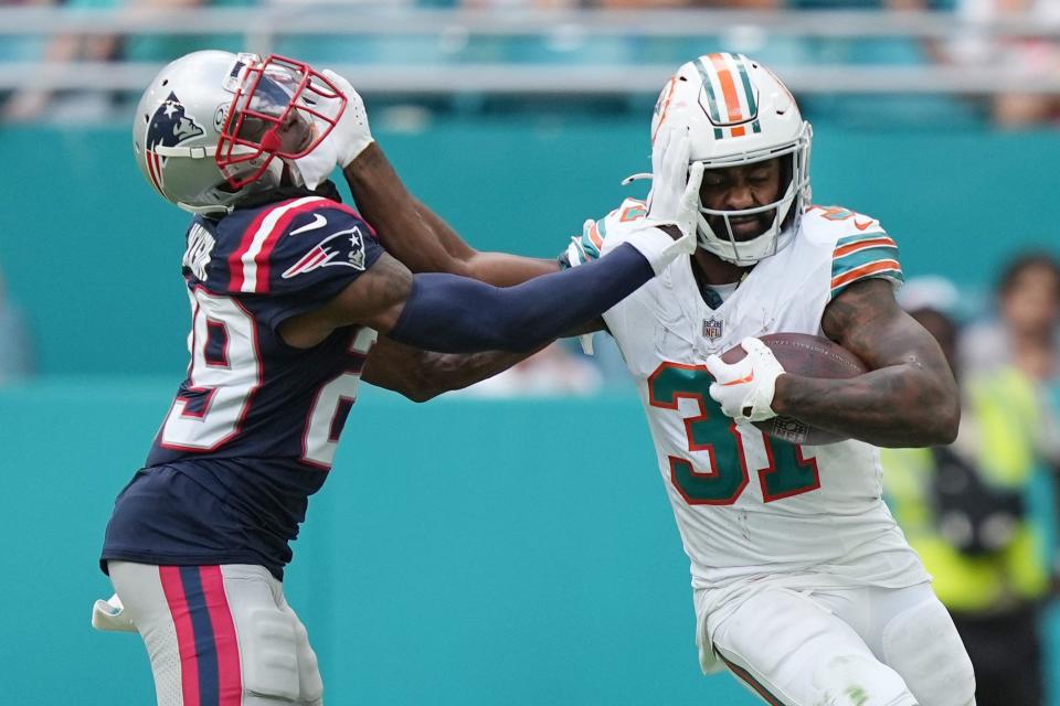 Dolphins running back Raheem Mostert gives Patriots cornerback J.C. Jackson a stiff-arm.