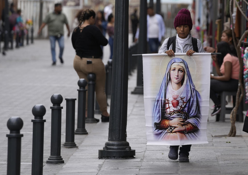 A woman carries a poster of The Virgin Mary in downtown Lima, Peru, Thursday, Dec. 8, 2022. Peru's political crisis moved forward Thursday, as former President Pedro Castillo appeared in court following a failed attempt to close congress and his successor looked for ways to unite the country. (AP Photo/Fernando Vergara)