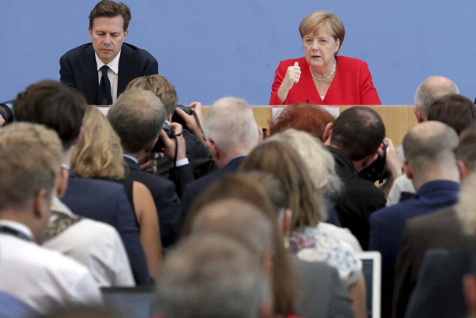 German Chancellor Angela Merkel, rear right, addresses the media during her annual sommer press conference in Berlin, Germany, Friday, July 19, 2019. (AP Photo/Michael Sohn)