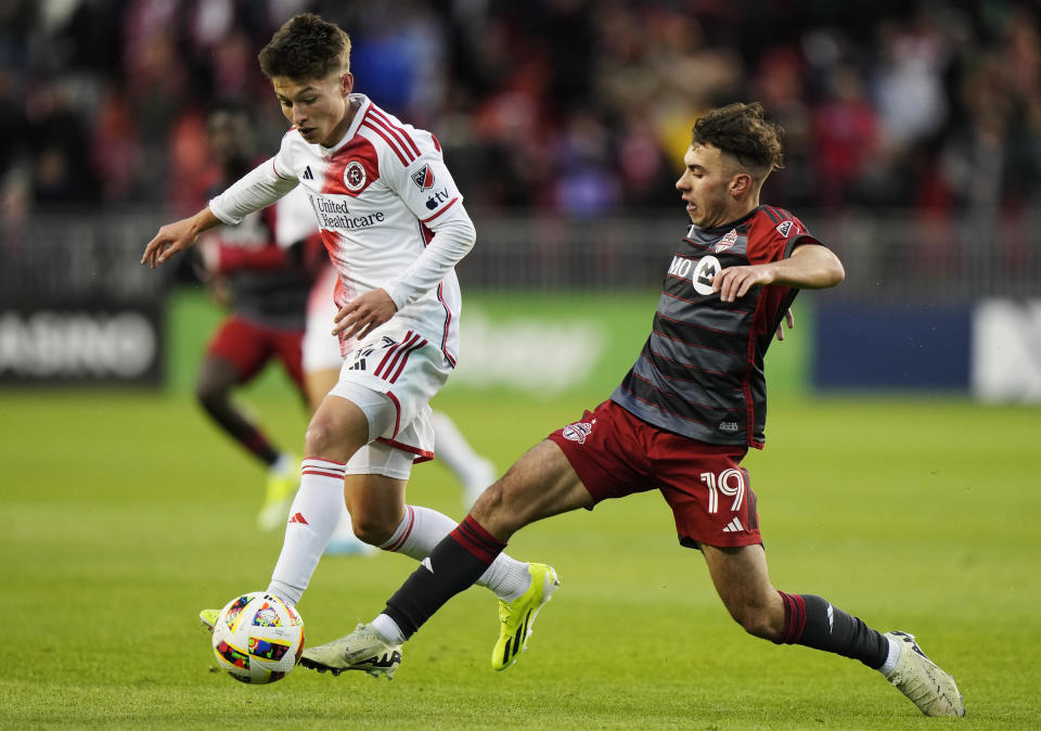 Toronto FC's Kobe Franklin (19) and New England Revolution's Esmir Bajraktarevic, left, vie for the ball during first-half MLS soccer match action in Toronto, Saturday, April 20, 2024. (Frank Gunn/The Canadian Press via AP)