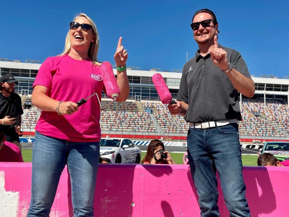 VP of BCBS of NC, Reagan Greene (left), and NASCAR Cup Series driver, Kurt Busch, paint the Charlotte Motor Speedway pit road walls pink ahead of the October race.