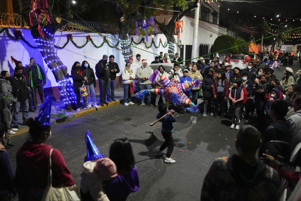 A boy hits a traditional Christmas "pinata" filled with fruit and candy during a Christmas "posada," which means lodging or shelter, in the Xochimilco borough of Mexico City, Wednesday, Dec. 21, 2022. For the past 400 years, residents have held posadas between Dec. 16 and 24, when they take statues of baby Jesus in procession to church for Mass to commemorate Mary and Joseph's cold and difficult journey from Nazareth to Bethlehem in search of shelter. (AP Photo/Eduardo Verdugo)