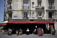 People sit on the terrace of a cafe in Paris, Tuesday, June 2, 2020. Parisians who have been cooped up for months with take-out food and coffee will be able to savor their steaks tartare in the fresh air and cobbled streets of the City of Light once more, albeit in smaller numbers. (AP Photo/Christophe Ena)