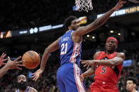 Toronto Raptors forward Precious Achiuwa (5) passes the ball past Philadelphia 76ers center Joel Embiid (21) during the first half of an NBA basketball game Thursday, April 7, 2022, in Toronto. (Frank Gunn/The Canadian Press via AP)