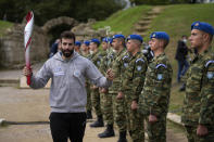 Skier Ioannis Antoniou, the first torch bearer, holds an olive branch during the final rehearsal for the lighting of the Olympic flame at Ancient Olympia site, birthplace of the ancient Olympics in southwestern Greece, Sunday, Oct. 17, 2021. The flame will be transported by torch relay to Beijing, China, which will host the Feb. 4-20, 2022 Winter Olympics. (AP Photo/Thanassis Stavrakis)