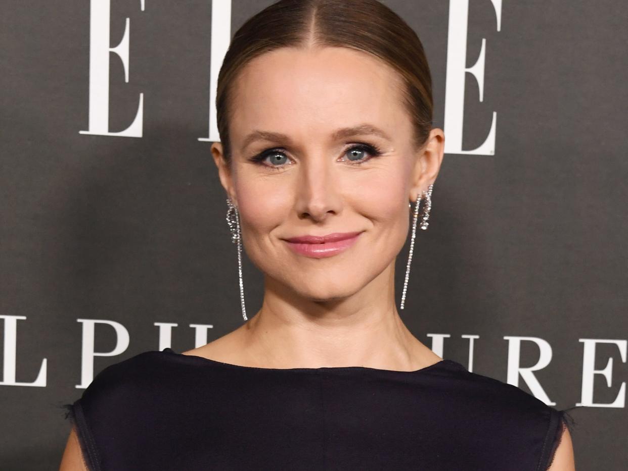 Kristen Bell poses for photos in a black dress and silver earrings.