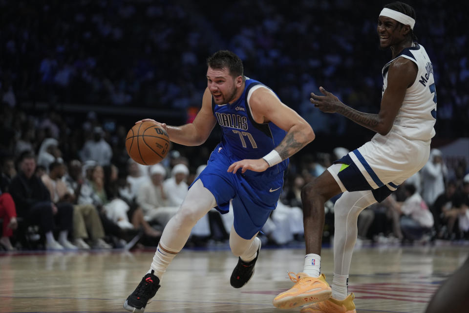 Luka Doncic of Dallas Mavericks drives past Jaden McDaniels of Minnesota Timberwolves during a preseason NBA game between Dallas Mavericks and Milwaukee Bucks Abu Dhabi, United Arab Emirates, Thursday, Oct. 6, 2023. (AP Photo/Kamran Jebreili)