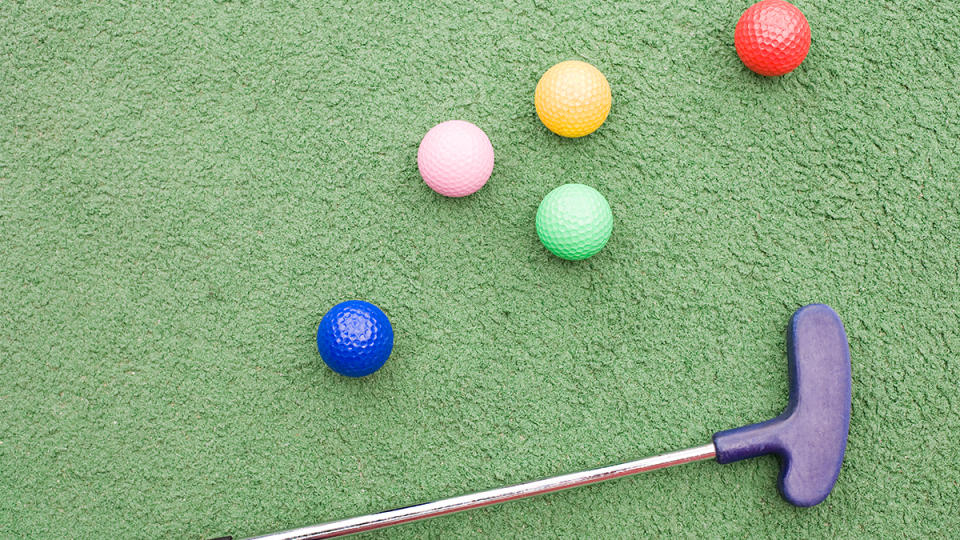 colorful golf balls and club on a mini golf course: mini golf tips